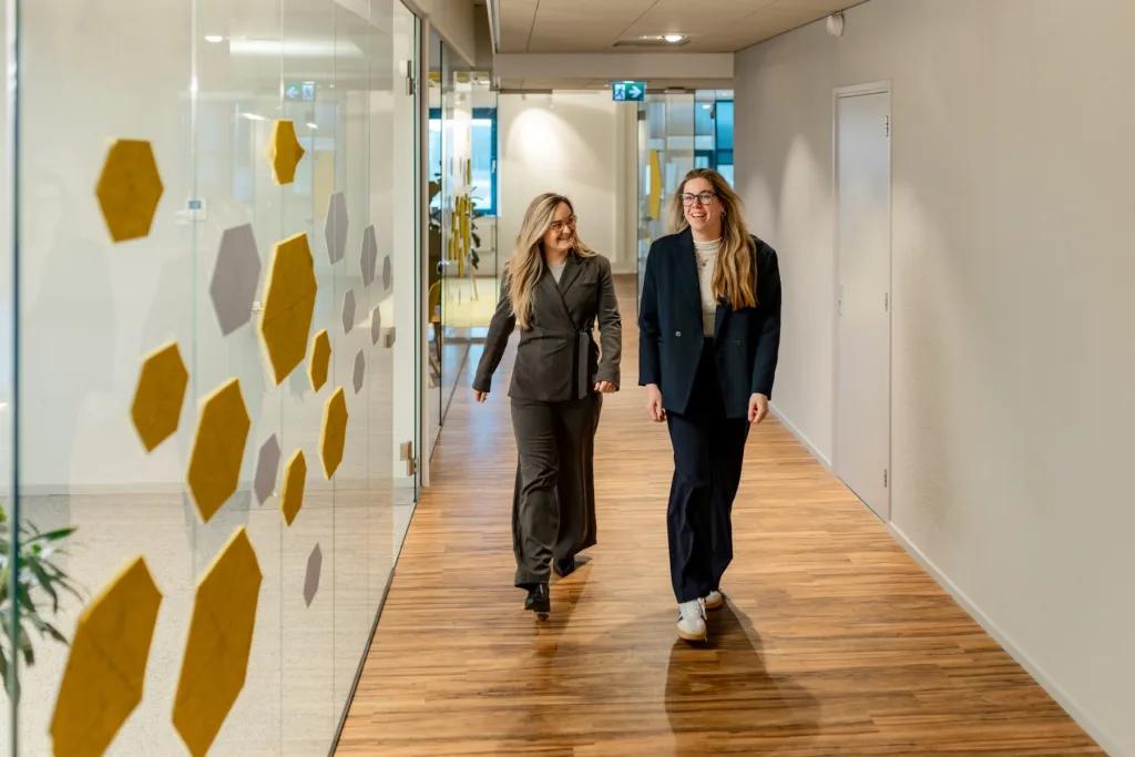 Twee collega’s lopen door de gang van een kantoor van OneLane